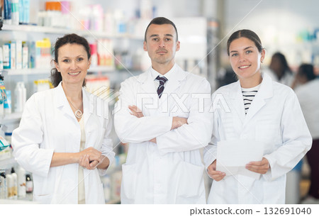 Three pharmacists in white doctor's robes posing together in chemist's shop Three pharmacists in white doctor's robes posing together in chemist's shop 132691040