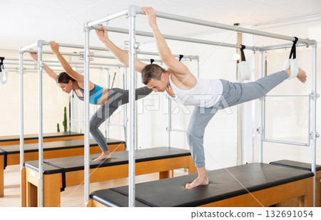 Girl and man is stretching body with pilates machine 132691054