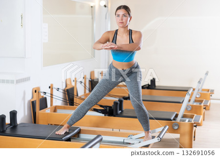 Girl practicing exercises on Pilates reformer during rehabilitation session Girl practicing exercises on Pilates reformer during rehabilitation session 132691056