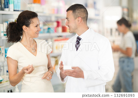 Male pharmacist consulting woman customer about medicament in box Male pharmacist consulting woman customer about medicament in box 132691093