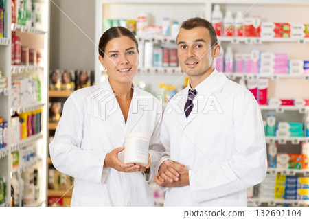 Young male and female pharmacists posing together in chemist's shop 132691104