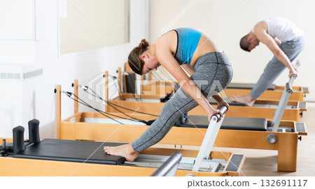 Girl doing stretching exercises on reformer in pilates studio 132691117