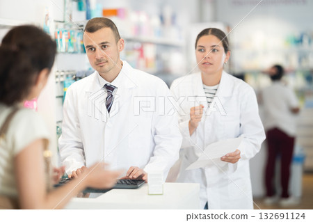 Man and woman pharmacists consulting woman on prescription medicine Man and woman pharmacists consulting woman on prescription medicine 132691124