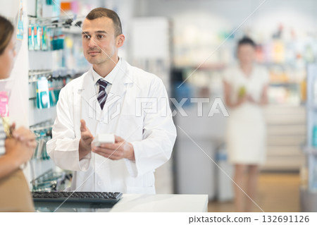 Male pharmacist speaking to woman customer buying medical preparation in drugstore 132691126