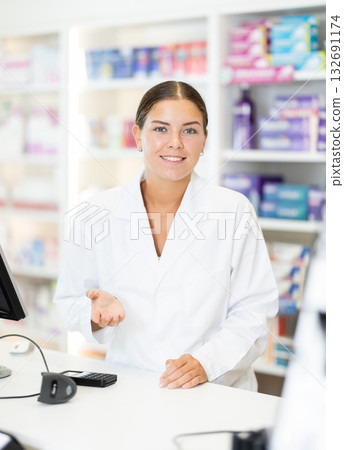 Young female pharmacist welcoming clients in chemist's shop 132691174