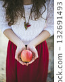 Woman in red skirt holding fresh apple in hands outdoors 132691493