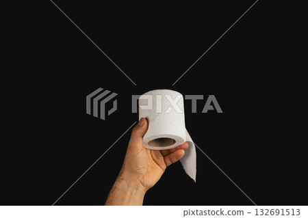 Holding a roll of toilet paper in a dark setting with a hand Holding a roll of toilet paper in a dark setting with a hand 132691513