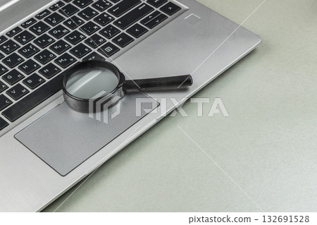 Magnifying glass on laptop keyboard showing close inspection setup 132691528