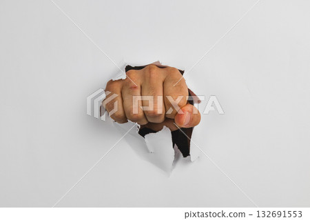 Fist breaking through wall creates striking visual impact 132691553