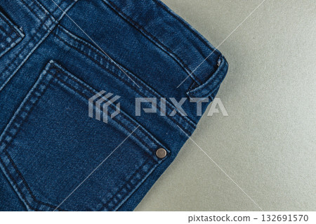 Denim jeans close-up showing pocket and stitching details on gray background Denim jeans close-up showing pocket and stitching details on gray background 132691570