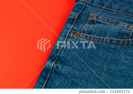 Blue denim jeans on a bright red background in a casual setting Blue denim jeans on a bright red background in a casual setting 132691572