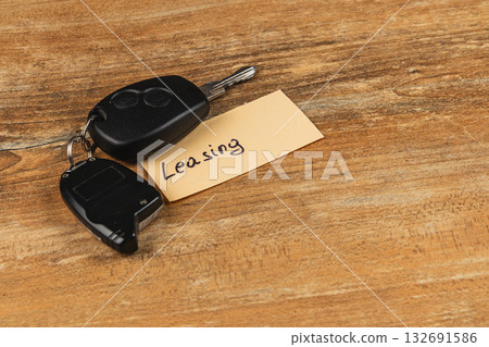 Keys on a wooden table with a note about leasing cars Keys on a wooden table with a note about leasing cars 132691586