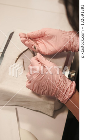Manicure tools. Nail procedure. Woman manicurist hands in sterilized pink gloves material taking forceps getting ready for beauty care. Manicure tools. Nail procedure. Woman manicurist hands in sterilized pink gloves material taking forceps getting ready for beauty care. 132691893