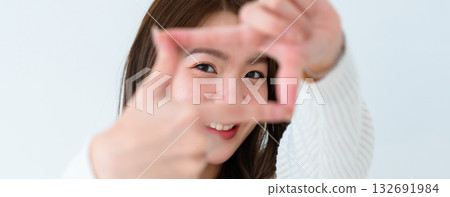 Closeup young Asian woman happy and making frame with fingers on white background in house Closeup young Asian woman happy and making frame with fingers on white background in house 132691984
