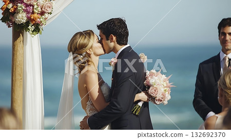 Bride and groom kiss in front of a white arch 132692370