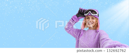 Woman in purple ski gear smiles with raised hand in snowy setting Woman in purple ski gear smiles with raised hand in snowy setting 132692762