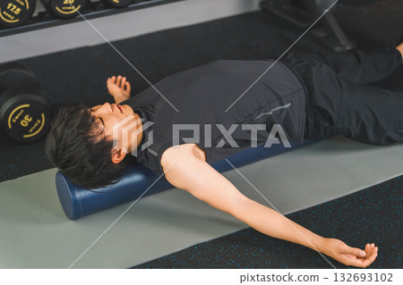 一名身穿運動服的男子正在使用健身桿進行伸展運動。 132693102