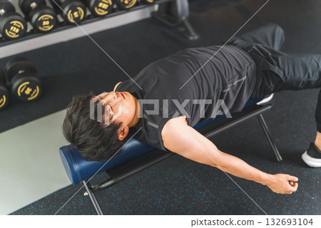 A man in sportswear stretching using an exercise pole A man in sportswear stretching using an exercise pole 132693104