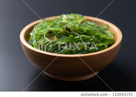 Wakame seaweed salad with sesame seed in a wooden bowl on black background Wakame seaweed salad with sesame seed in a wooden bowl on black background 132693155