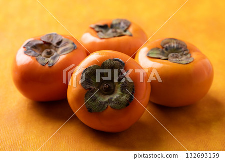 Ripe persimmon fruit on orange color background, Autumn fruit Ripe persimmon fruit on orange color background, Autumn fruit 132693159