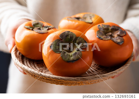 Ripe persimmon fruit in basket holding by hand, Autumn fruit Ripe persimmon fruit in basket holding by hand, Autumn fruit 132693161