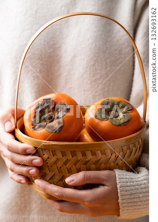 Ripe persimmon fruit in basket holding by hand, Autumn fruit Ripe persimmon fruit in basket holding by hand, Autumn fruit 132693162