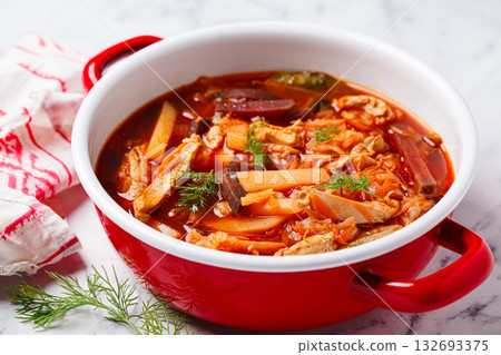 Classic borscht with chicken in a red pot. 132693375