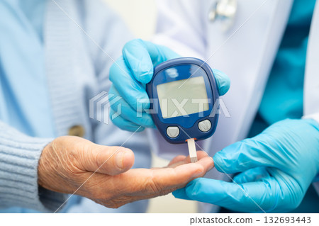 Asian doctor using digital glucose meter for check sample blood sugar level to treatment diabetes. 132693443