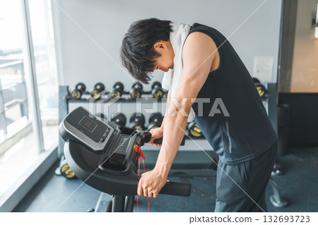 Young Asian man doing aerobic exercise on a walking machine in a sports gym 132693723