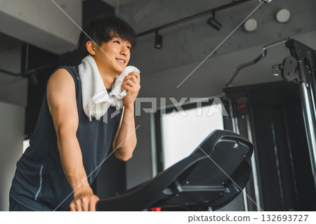 亞洲年輕男子在體育館的步行機上進行有氧運動 132693727