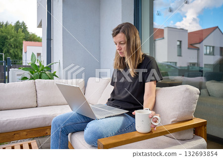 Woman working with laptop and coffee on terrace sofa 132693854