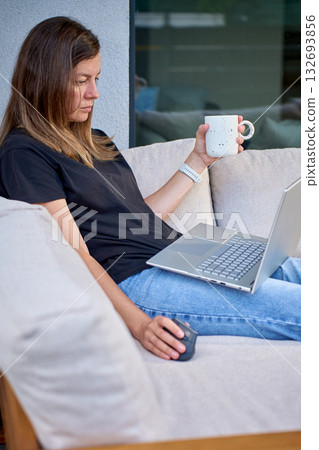 Woman working with laptop and coffee on terrace sofa 132693856