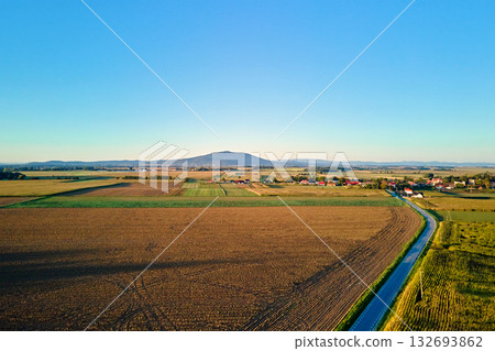 Aerial view of rural landscape with distant mountain and village Aerial view of rural landscape with distant mountain and village 132693862