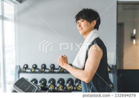 Young Asian man doing aerobic exercise (jogging) on a walking machine in a sports gym 132694079