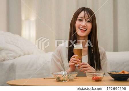 Young Asian woman having a drink in the bedroom at home (beer, home drinking, drinking habits) 132694396