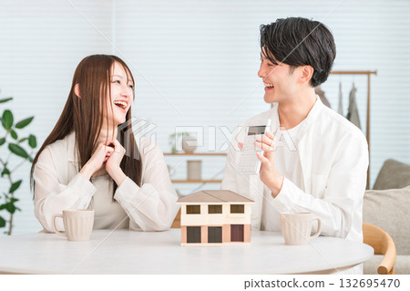 一對年輕的亞洲夫婦一邊看著房屋模型一邊討論他們的購屋預算。 132695470