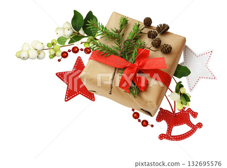 Christmas gift box with ribbon bow, fir-tree twig and small cones in a corner holiday arrangement with snowberries and decorations isolated on white Christmas gift box with ribbon bow, fir-tree twig and small cones in a corner holiday arrangement with snowberries and decorations isolated on white 132695576