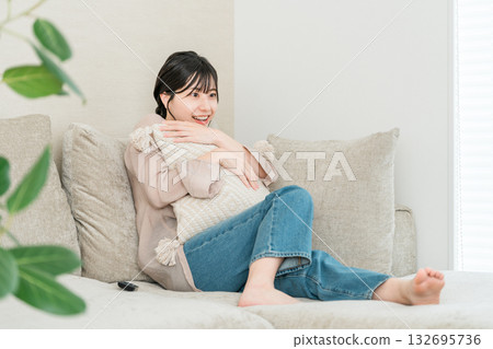 Young Asian woman sitting on the sofa in the living room watching TV or a movie 132695736