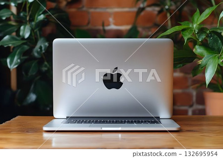 Sleek Silver Laptop Resting on a Wooden Table Amidst Lush Greene Sleek Silver Laptop Resting on a Wooden Table Amidst Lush Greene 132695954