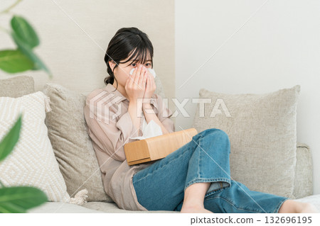 亞洲年輕女性在沙發上看電視或電影時擦眼淚 132696195