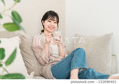 Relaxing Asian woman drinking a mug of coffee, tea, or hot water at home (warming up) 132696401