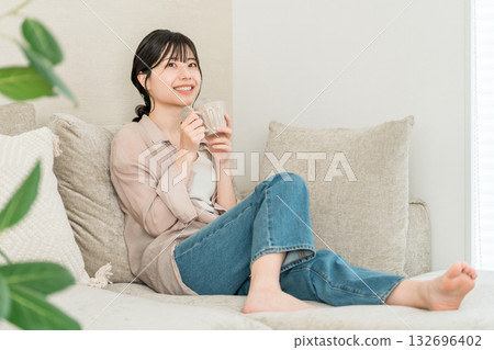 一位放鬆的亞洲女性在家中喝著咖啡、茶或熱水（暖暖身子）。 132696402