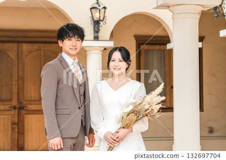 身著婚紗的新郎新娘在婚禮教堂裡手捧乾燥花和花環。 132697704