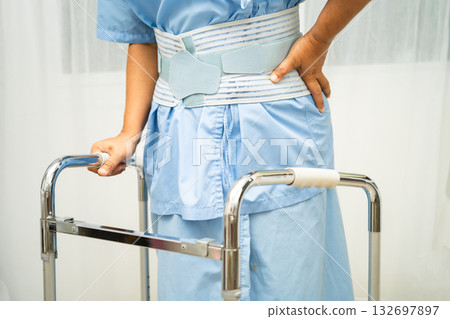 Asian senior pain back wearing elastic support belt with walker. 132697897