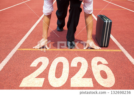 Happy new year 2026 concept. Business Man preparing to run on athletics track engraved with the year 2026. Happy new year 2026 concept. Business Man preparing to run on athletics track engraved with the year 2026. 132698236