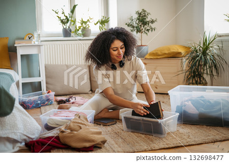 Young woman sorting wardrobe indoors at home, charity donation concept. Young woman sorting wardrobe indoors at home, charity donation concept. 132698477