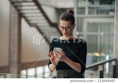Portrait of young businesswoman reading email on smartphone. 132698485
