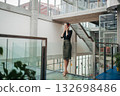 Businesswoman with headphones standing in modern openspace office building. 132698486
