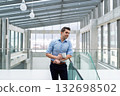 Young businessman standing indoors in an office, holding coffee cup. 132698502