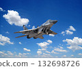 Fighter jet flying high against a backdrop of blue sky and white clouds 132698726